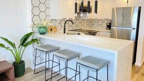 A modern kitchen with a white island, stainless steel appliances, and a hexagonal tile backsplash.