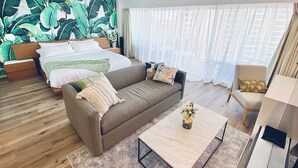 A hotel room with a bed, a sofa, a coffee table, and a chair.