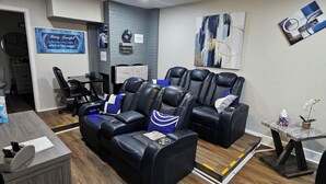 A modern living room with a sectional sofa, a massage chair, and a small table with a plant.