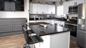 A modern kitchen with white cabinets, stainless steel appliances, and a central island with bar stools.