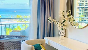 A modern room with a view of the ocean, a round mirror, a white desk, and a comfortable chair. - Oceanfront Paradise (Car Available) (Honolulu)
