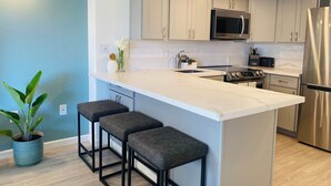 A modern kitchen with a central island, stainless steel appliances, and light-colored cabinetry.
