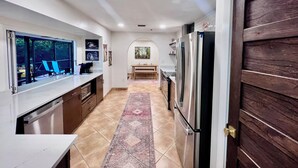 A modern kitchen with a large island, stainless steel appliances, and a view through the window. - Paradise awaits! Heated pool, huge lanai, outdoor oasis close to downtown Naples (Naples)