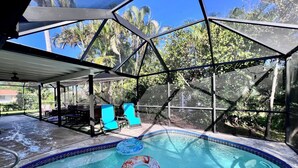 A covered swimming pool with clear blue water, surrounded by a glass enclosure, and a patio area with outdoor furniture. - Paradise awaits! Heated pool, huge lanai, outdoor oasis close to downtown Naples (Naples)