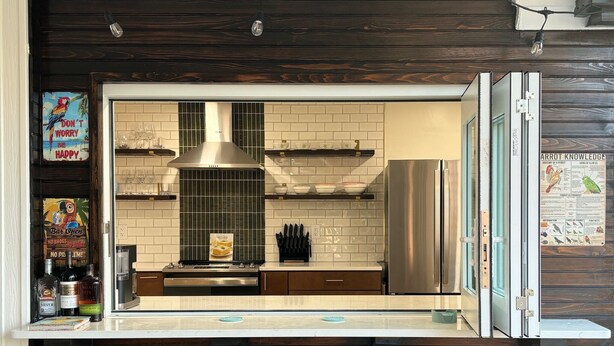 A modern kitchen with dark wooden cabinetry, a stainless steel range hood, and a built-in oven. - Paradise awaits! Heated pool, huge lanai, outdoor oasis close to downtown Naples (Naples)
