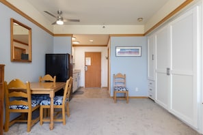 A dining area with a wooden table and chairs, a ceiling fan, a refrigerator, and a door leading to another room. - 2756 Slopeside Condo (Keystone)