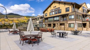 Un hotel con terraza al aire libre, fachada de piedra y varios balcones.