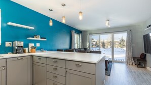 Une cuisine moderne dotée d’un grand îlot central, d’appareils électroménagers intégrés et de luminaires suspendus.