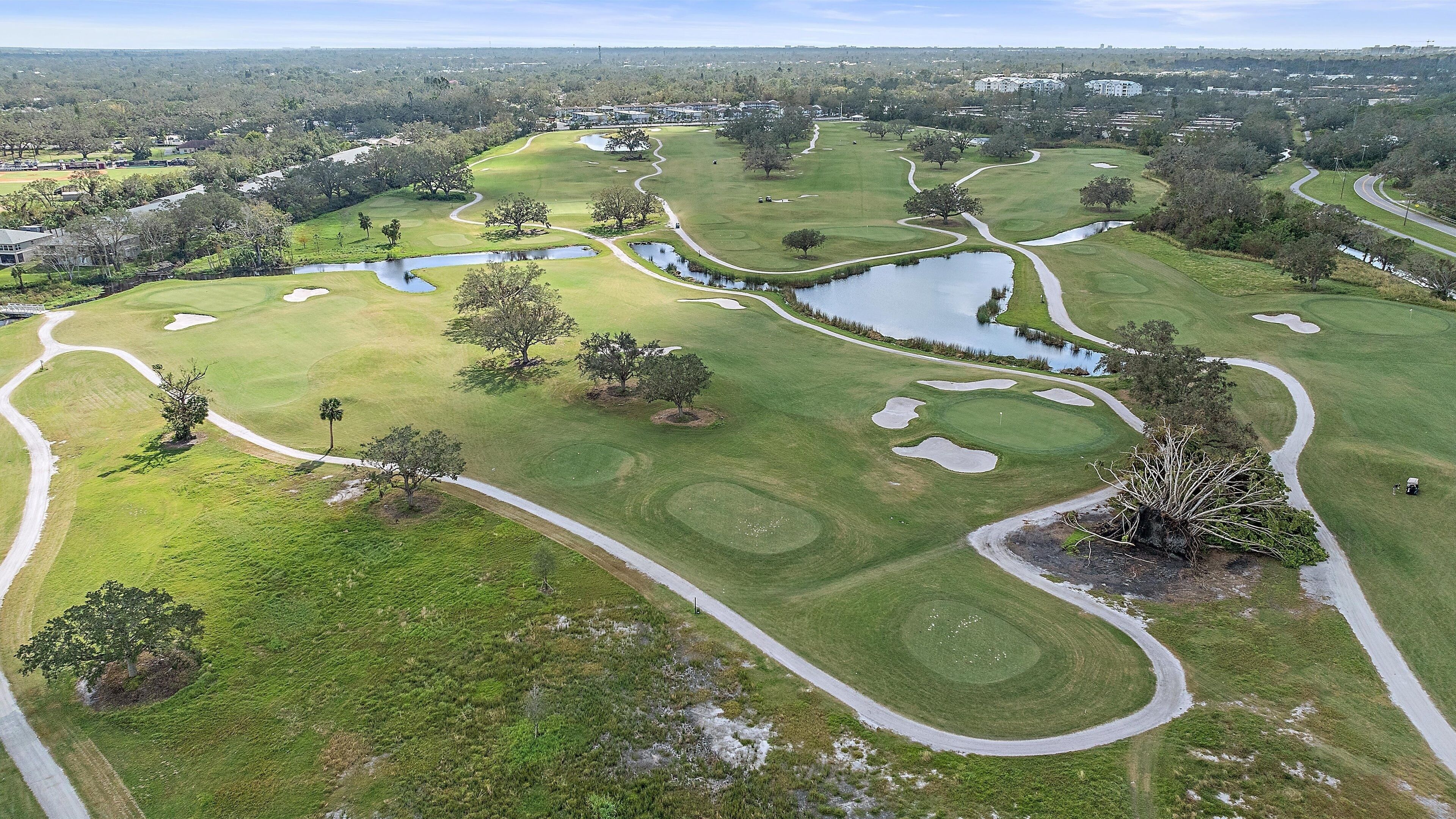 Eine Vogelperspektive auf einen Golfplatz mit mehreren Bunkern, Wasserhindernissen und einem gepflegten Fairway.