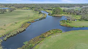 A river meandering through a park with grassy banks and scattered trees. - Tee Time On Breezemont 3 Bedroom Home (Sarasota)
