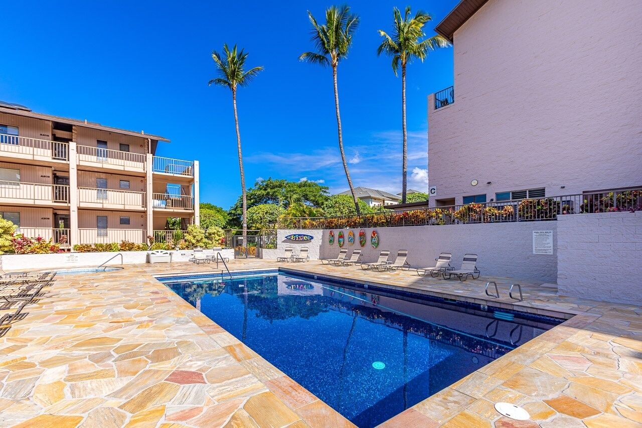 Une piscine avec des chaises longues et un bâtiment doté de balcons.