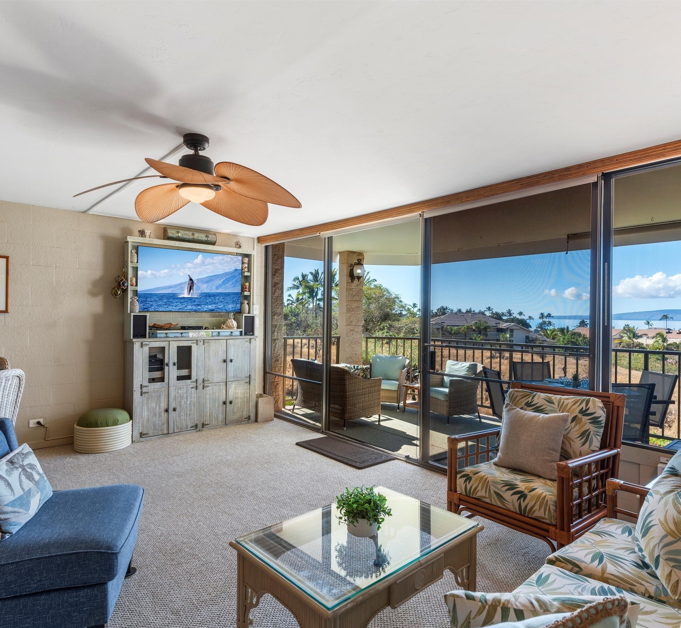 A spacious living area with a large TV, comfortable seating, and a balcony with a view.