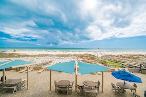 A beachside patio with outdoor seating and a view of the beach.