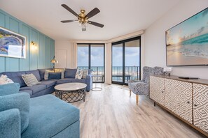 A modern living room with a sofa, armchairs, a coffee table, a patterned cabinet, and a ceiling fan. - Phoenix X 213 3 Bedroom Condo (Orange Beach)
