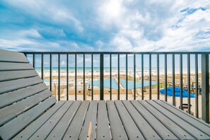 Une terrasse en bois avec vue sur une plage et une piscine.