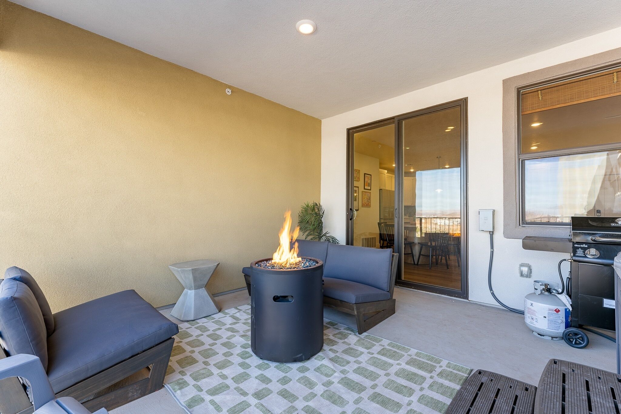 Eine Terrasse mit Feuerstelle, Sitzgelegenheiten und Grillbereich.