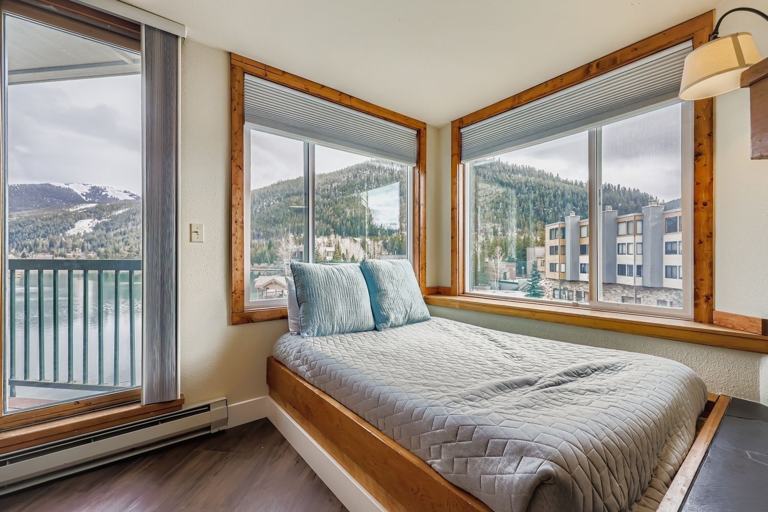 A bedroom with a bed, large windows, and a view of a mountainous landscape.