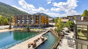 A modern hotel with a riverside patio, stone facade, and a view of a mountain. - 1483 Lakeside 1 Bedroom Condo (Keystone)