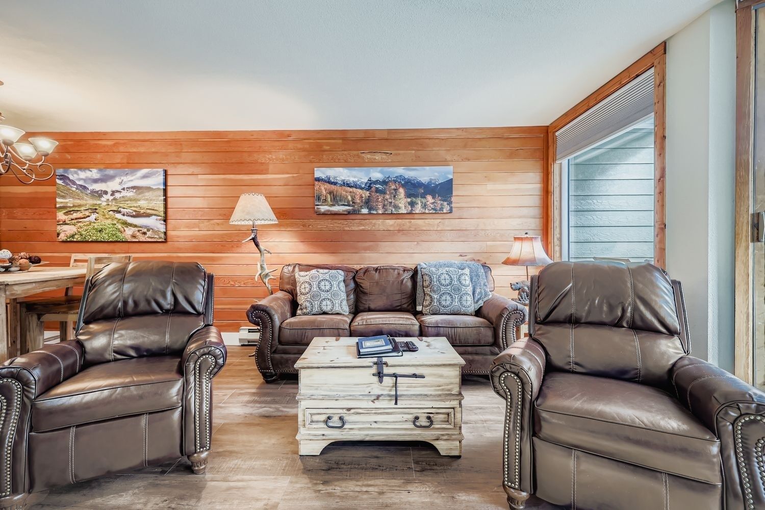 A living room with leather sofas, a wooden coffee table, and two lamps.