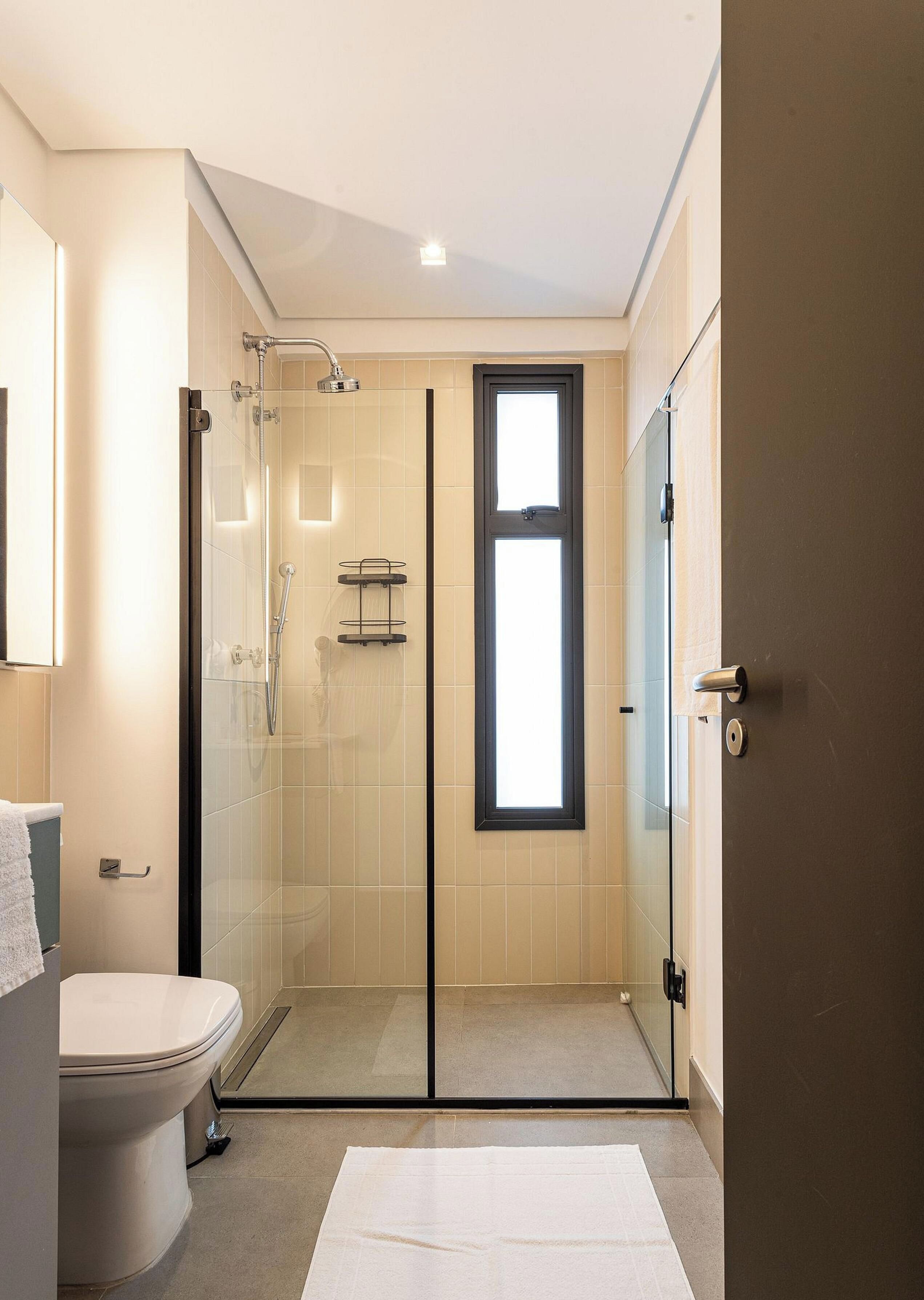 Un baño moderno con cabina de ducha de vidrio, inodoro y ventana.