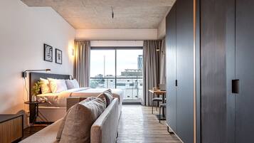 Una habitación de hotel moderna con cama, sofá y escritorio con silla.