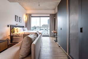 A modern hotel room with a bed, sofa, and a desk with a chair. - Apartamentos com vista incrível para São Paulo ao lado da Rebouças e Faria Lima - Pinheiros (São Paulo)