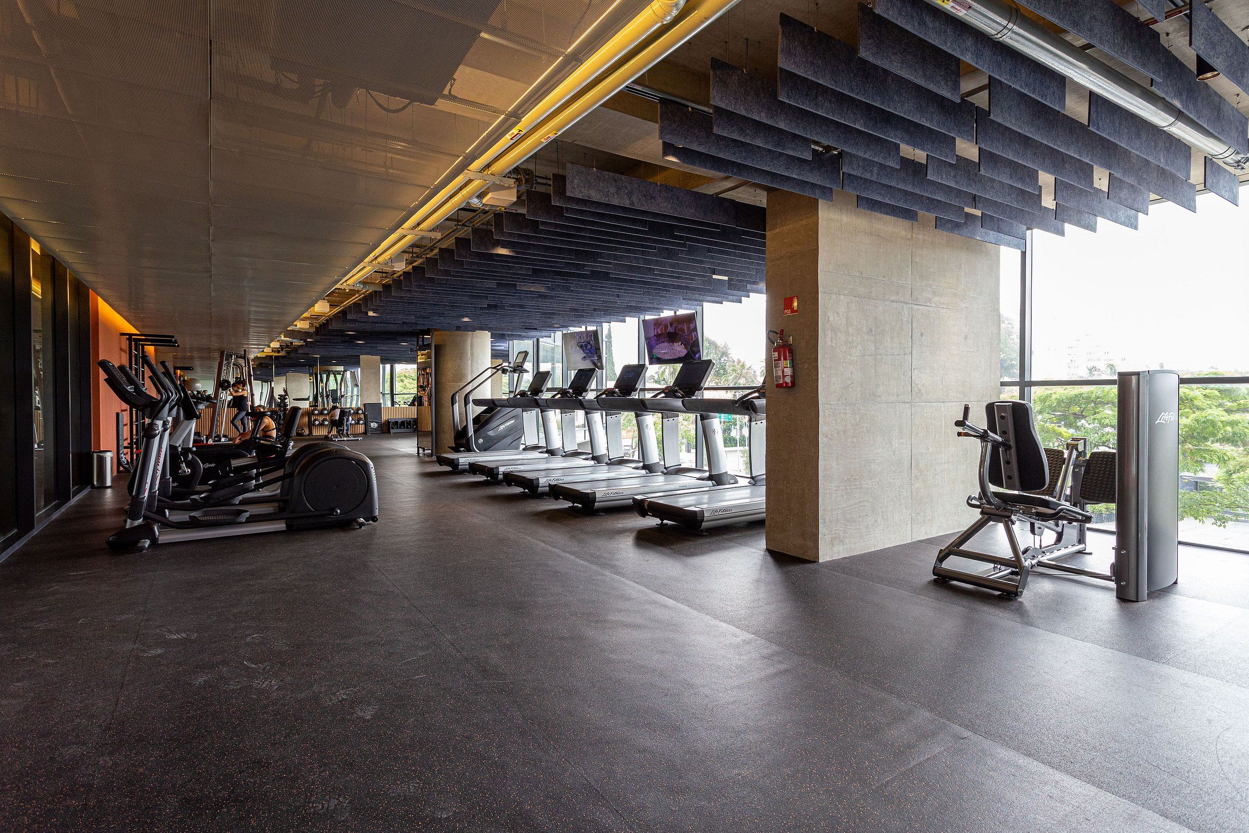 A modern gym with treadmills, elliptical machines, and weight equipment.