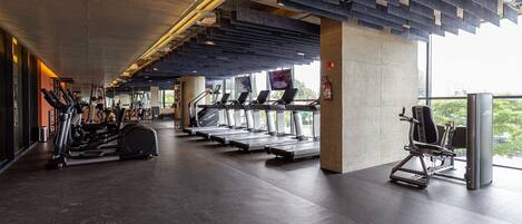 A modern gym with treadmills, elliptical machines, and weight equipment.
