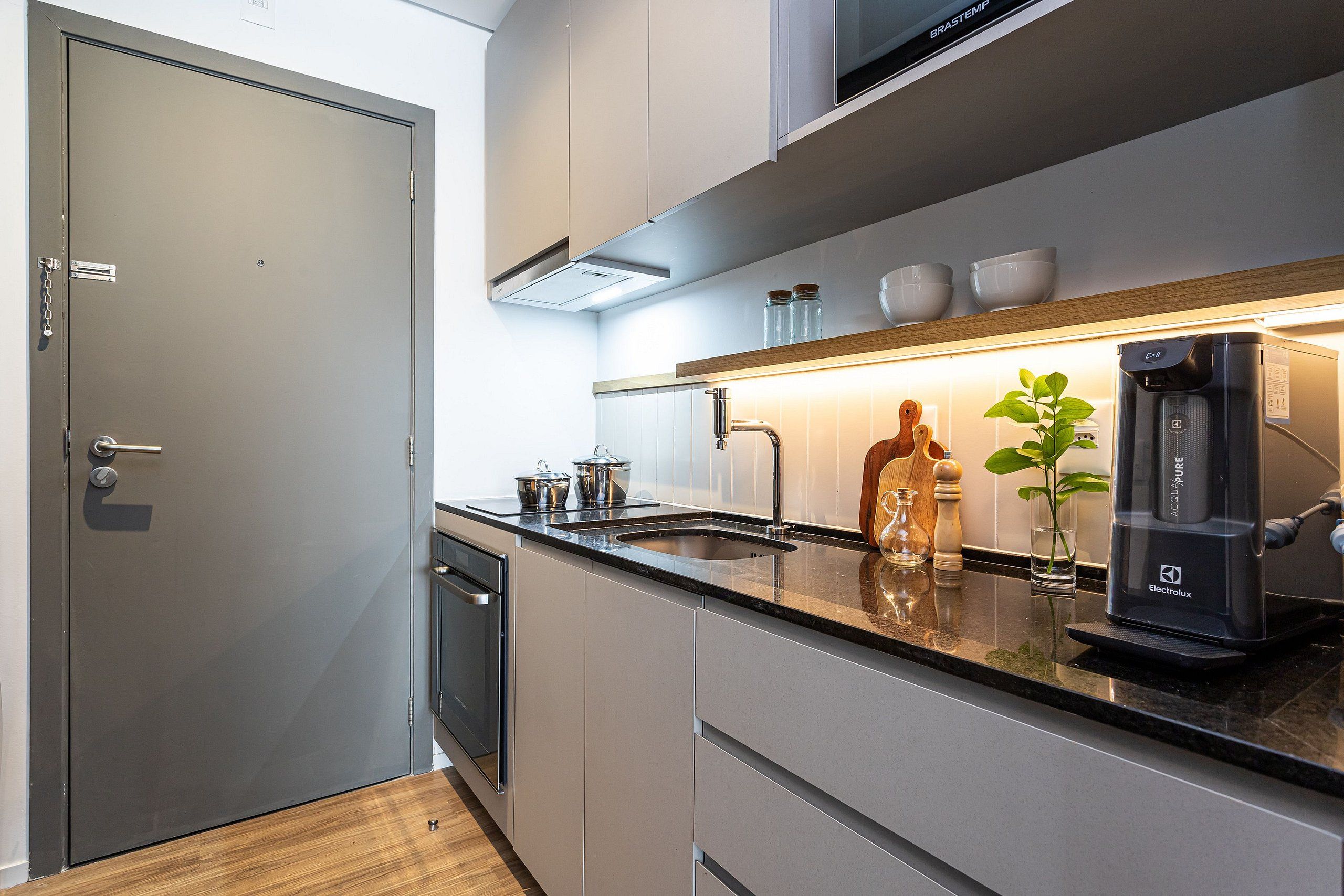 Una cocina moderna con lavavajillas integrado, cafetera y pileta.