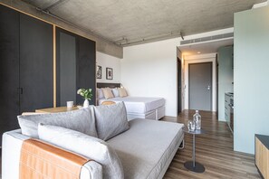 A modern living space with a sofa, a bed, a small table, and a kitchenette area. - Apartamentos com vista incrível para São Paulo ao lado da Rebouças e Faria Lima - Pinheiros (São Paulo)
