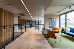 A modern interior with a long corridor, seating area with sofas and chairs, and large windows. - Apartamentos com vista incrível para São Paulo ao lado da Rebou ças e Faria Lima - Pinheiros (São Paulo)