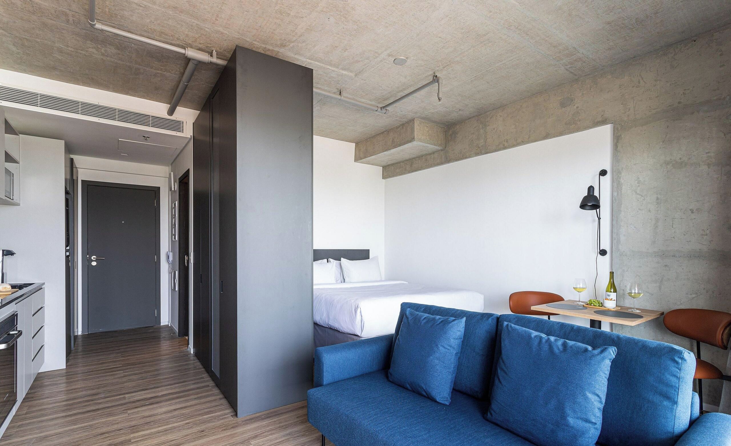 Una habitación de hotel moderna con sofá, cama, escritorio y zona de comedor.