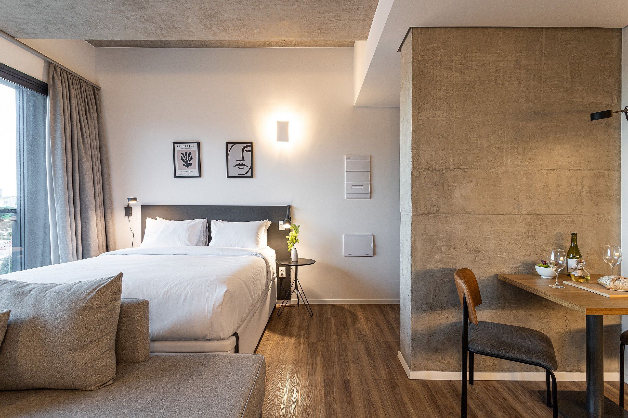 Une chambre d’hôtel comprenant un lit, un coin salon, une table à manger avec des chaises et une vue sur l’extérieur.