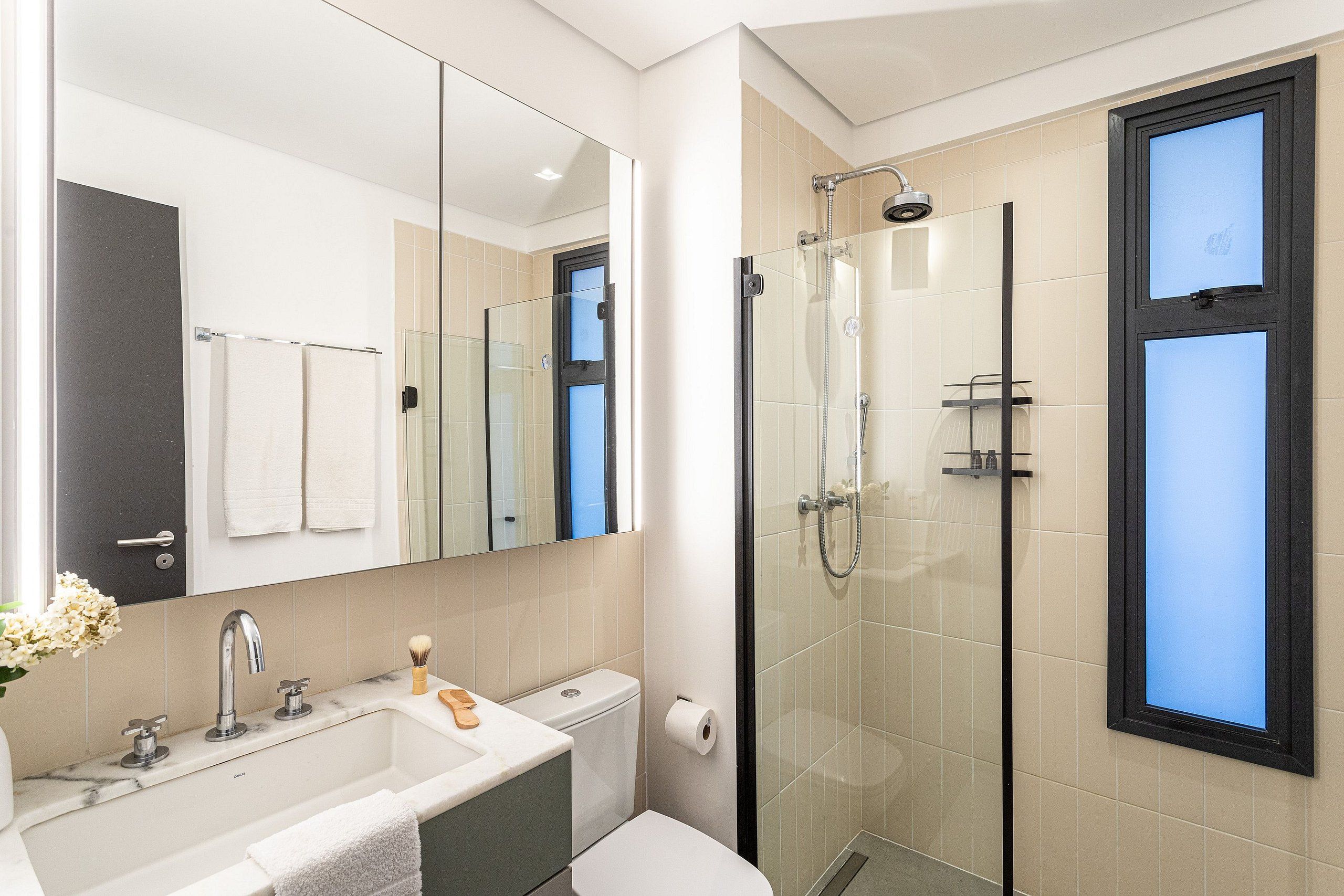 Un bagno moderno con doccia vetrata, lavandino con specchio e servizi igienici.
