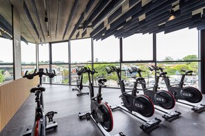 A gym with stationary bikes, a wooden wall, and large windows with a city view. - Apartamentos com vista incrível para São Paulo ao lado da Rebouças e Faria Lima - Pinheiros (São Paulo)