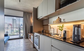 A modern kitchen with a built-in oven, a coffee machine, and a view of the city through large windows. - Apartamentos com vista incrível para São Paulo ao lado da Rebouças e Faria Lima - Pinheiros (São Paulo)