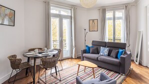 A living room with a sofa, chairs, a dining table, and a chandelier. - Le Milady - Charmant appartement au cœur de Rennes (Rennes)