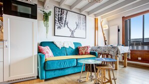 En moderne stue med en turkis sofa, et lille rundt bord og et spisebord med stole.