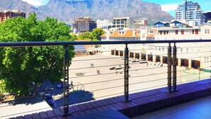 Une vue depuis un balcon donnant sur un parking, avec des bâtiments et des montagnes en arrière-plan.