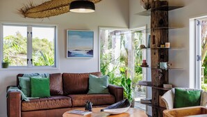 Ein modernes Wohnzimmer mit einer Ledersofa, einem Holztisch und einem Bücherregal an einer Wand mit einem großen Fenster.