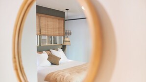 A bedroom with a bed, pillows, a headboard, and a hanging lamp.