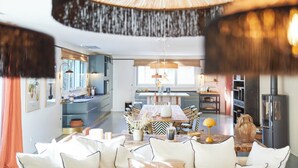 A modern kitchen with a central island, a dining area with a table and chairs, and a living room with a sofa and decorative items.