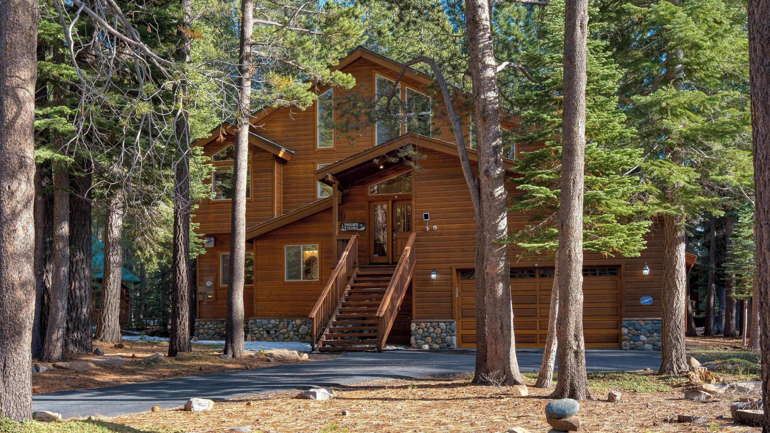 A log cabin with a staircase leading to the entrance, surrounded by trees.
