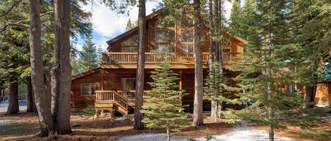 A cabin with a wooden exterior, a balcony, and a deck.