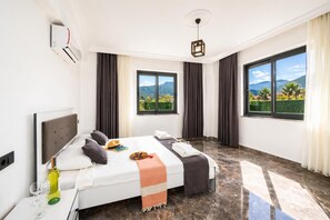 A hotel room with a bed, a TV, a window with a view, and a ceiling light.