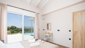 A bedroom with a large bed, a bedside table, a mirror, and a view of a pool and greenery. - Casa di Pietra - Two Bedroom Villa, Sleeps 4 (Lakithra)