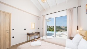 A bedroom with a large bed, a desk, a chair, and a view of a swimming pool and landscape. - Casa di Pietra - Two Bedroom Villa, Sleeps 4 (Lakithra)