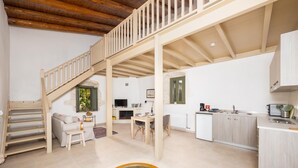 Un vaste espace de vie comprenant un escalier en bois, un coin repas, une cuisine et une grande fenêtre.