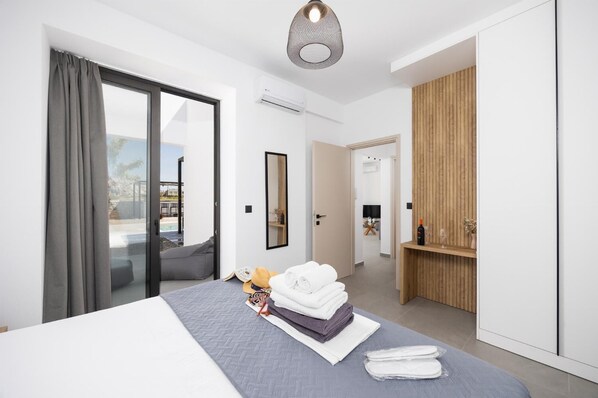 Ein modernes Hotelzimmer mit Bett, einem Holzkonsolenmöbel, einem Spiegel und Blick ins Freie.