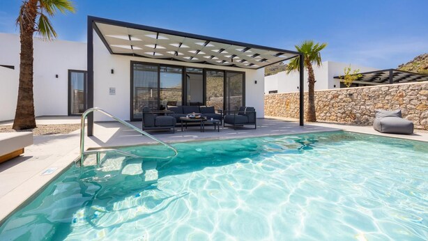 Een modern huis met een zwembad, buitenmeubels en een pergola.